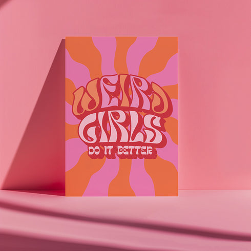 Retro-style poster with psychedelic 1970s-inspired design. Text reads "WEIRD GIRLS DO IT BETTER" in wavy, groovy lettering. Pink and orange sunburst background. Centered text surrounded by curved rays. Bold red frame with scalloped edges. Vibrant colors and playful typography create a vintage hippie vibe. Square format print with rounded corners. Perfect for fans of retro aesthetics and empowering slogans.